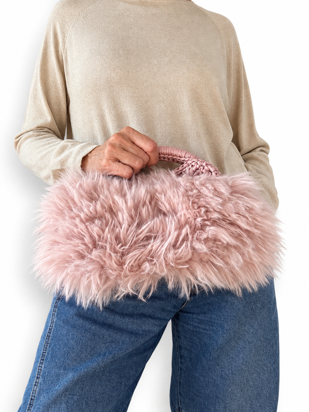 Clutch Greta rosa in ecopelliccia indossata a mano con jeans e maglia beige