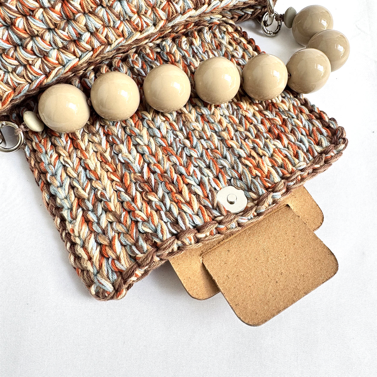 Dettaglio del manico con grandi perle della borsa crochet Kia Cuoio Chiaro.