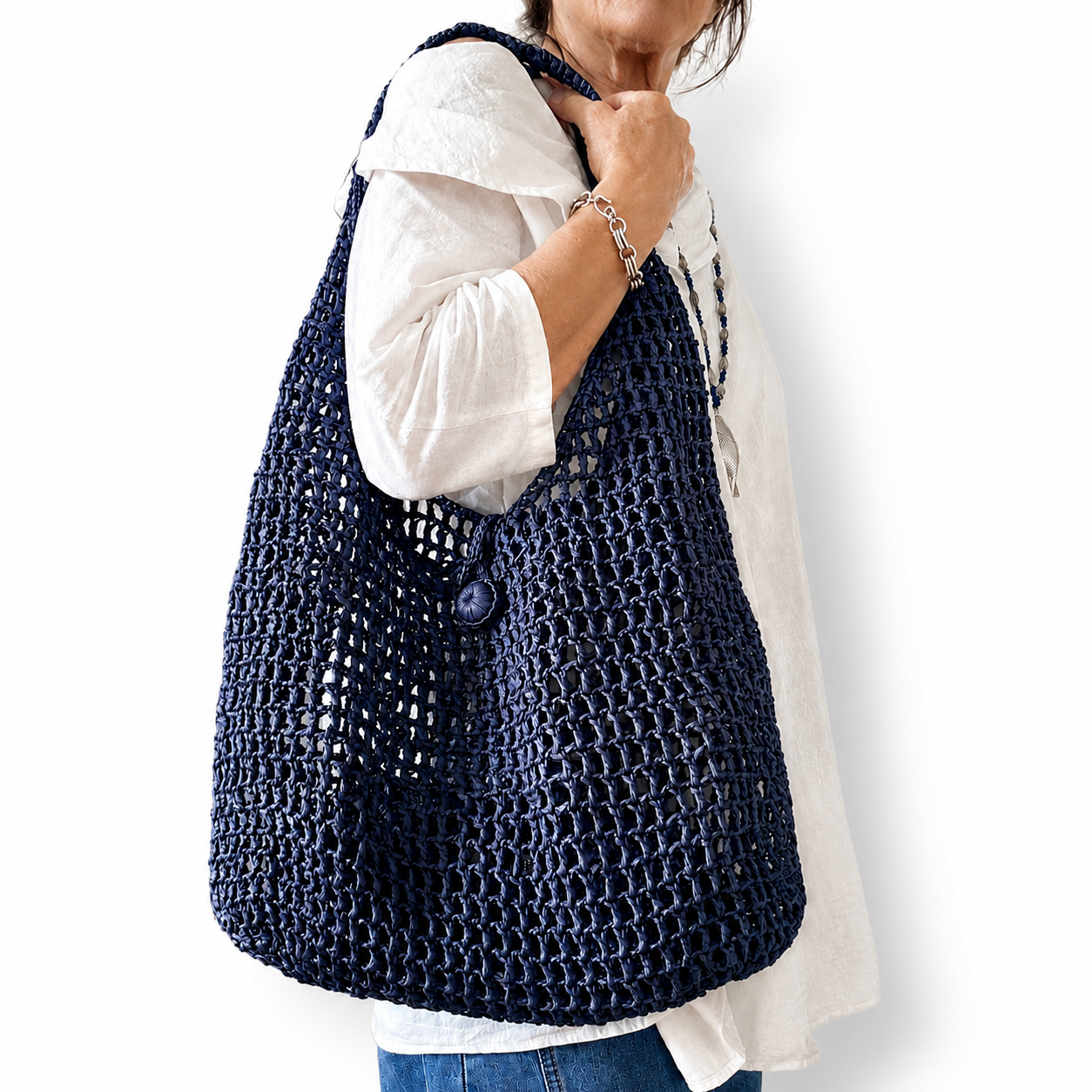 Maris, borsa artigianale in rafia blu realizzata a mano all'uncinetto con pochette coordinata, indossata a spalla.
