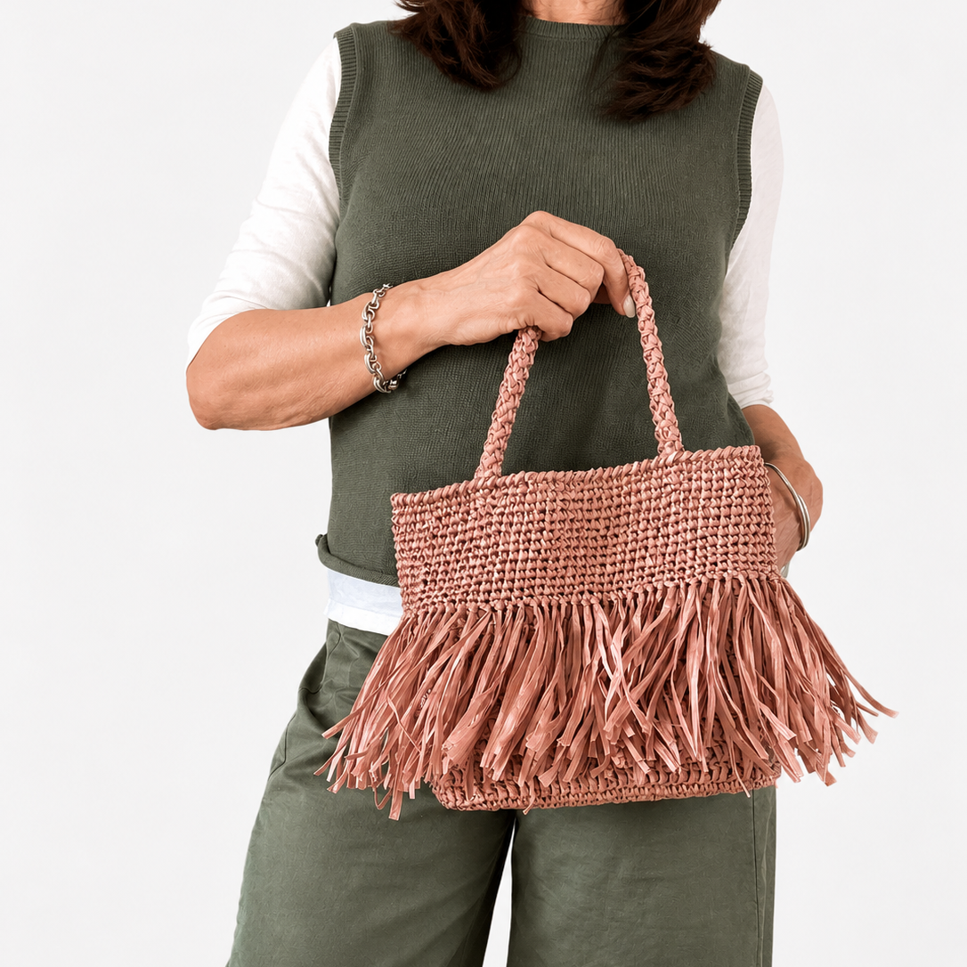Modella con borsa in rafia rosa con frange della Collezione Mediterranea
