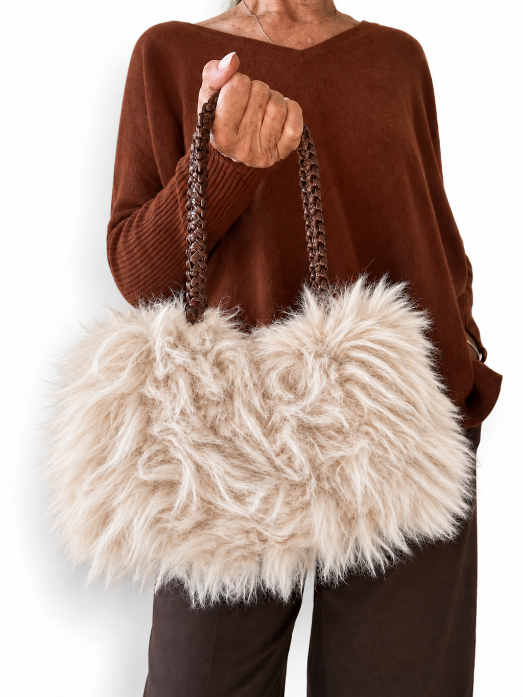 Borsa Sveva in ecopelliccia naturale indossata a mano, con manici intrecciati marroni e outfit autunnale.